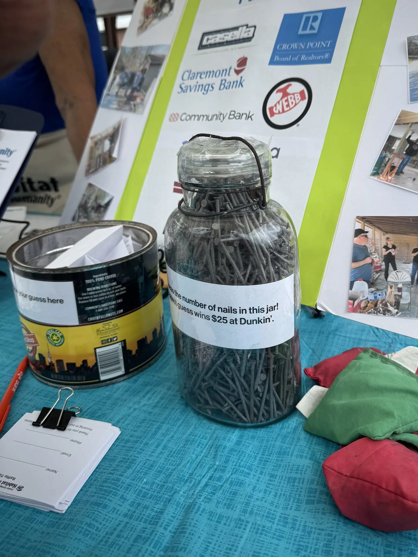 A glass jar full of nails with a sign reading "Guess the number of nails in this jar"