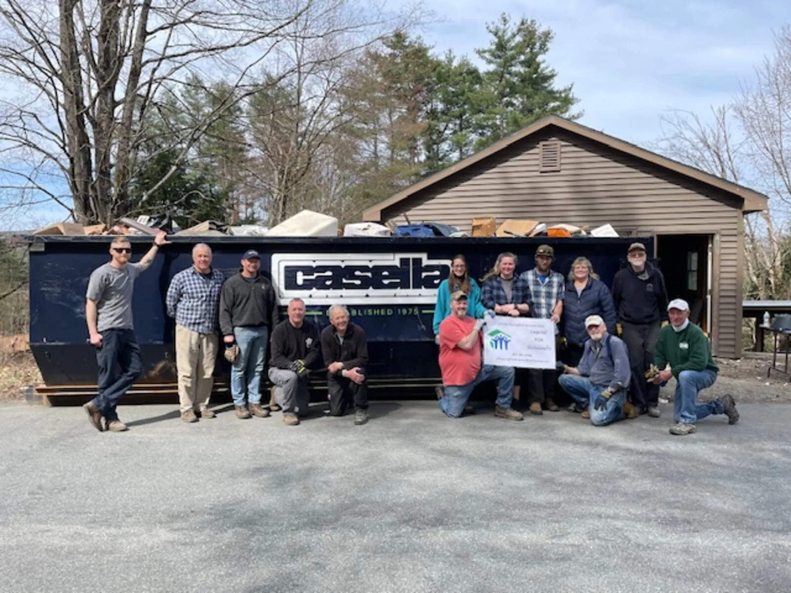 Volunteer crew posed with a rubbish dumpster during a site cleanup