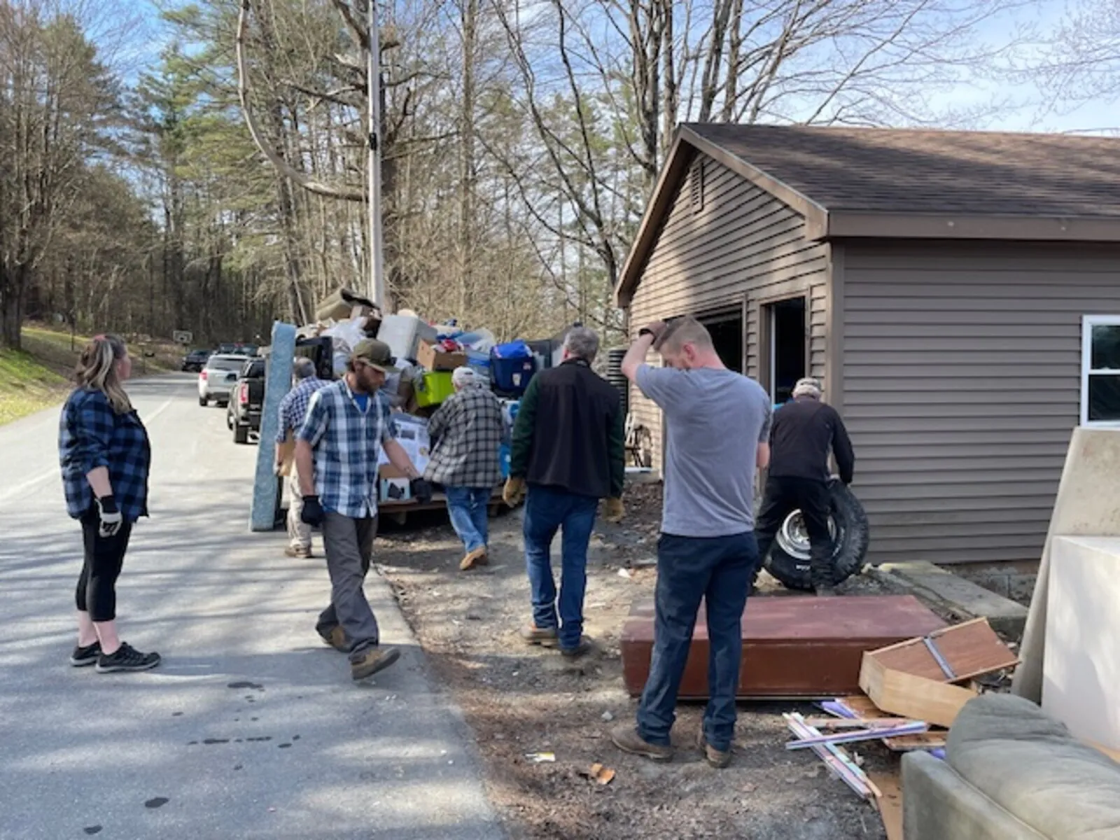 Volunteers loading debris into a dumpster on a work site
