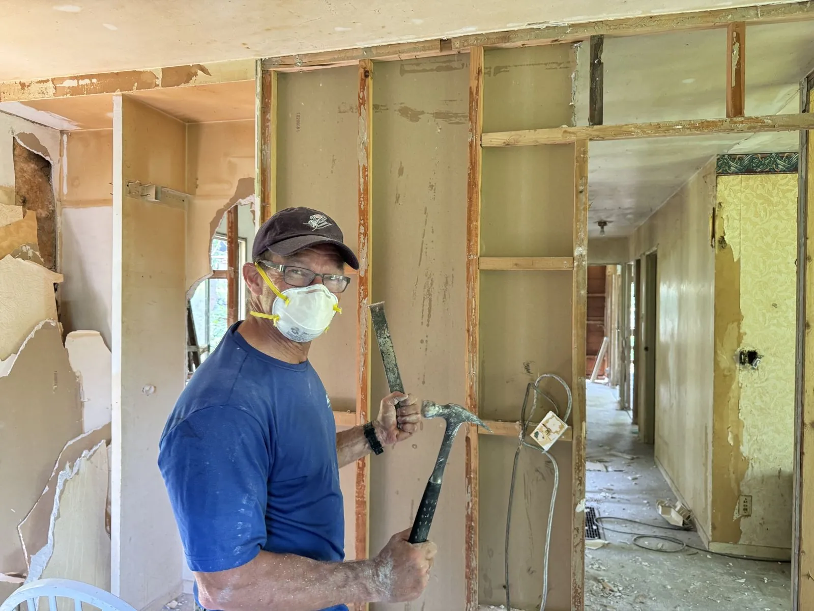 Volunteer in a dust mask removing old plaster during demolition