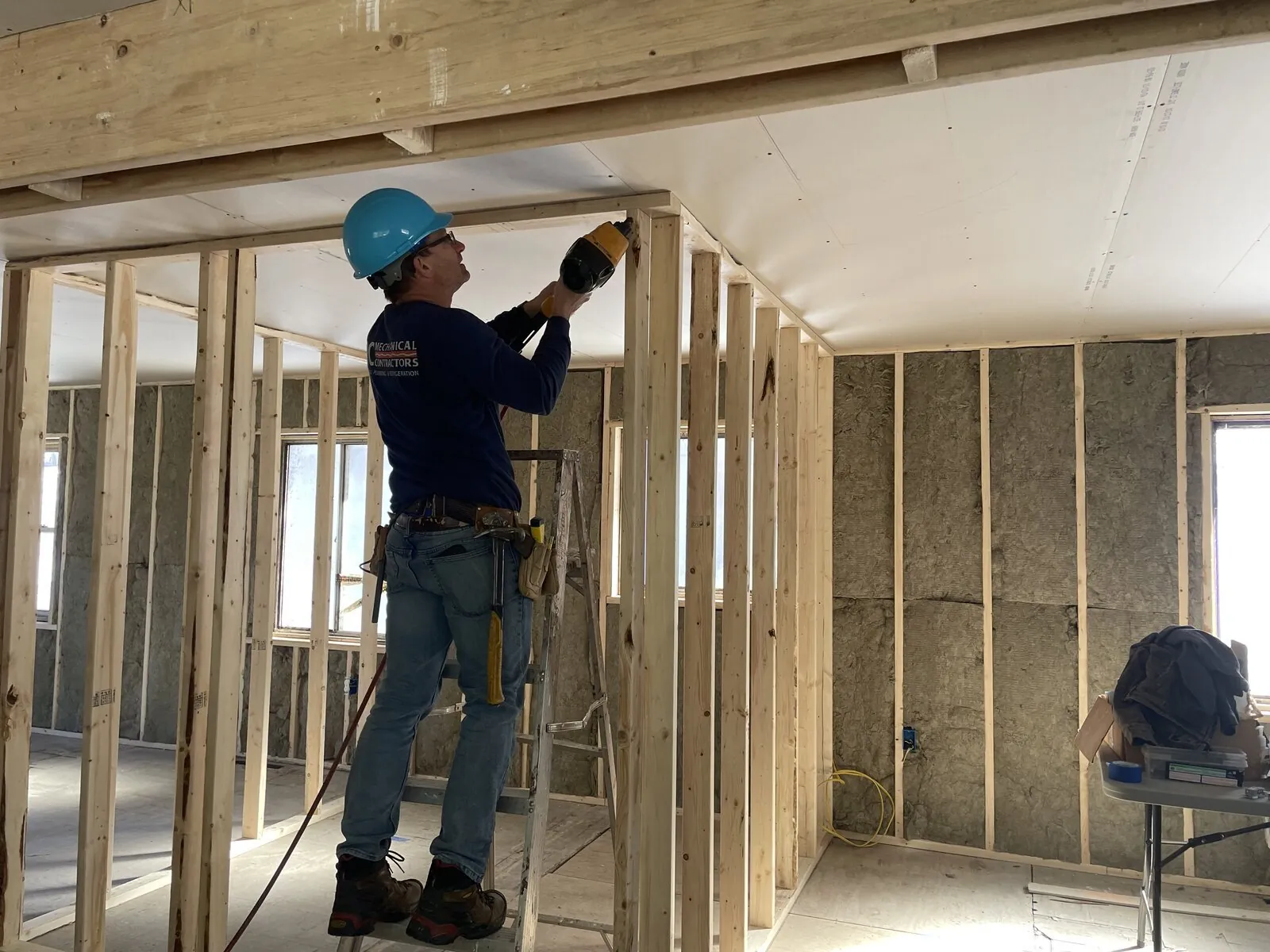 Volunteers in hard hats framing an interior wall