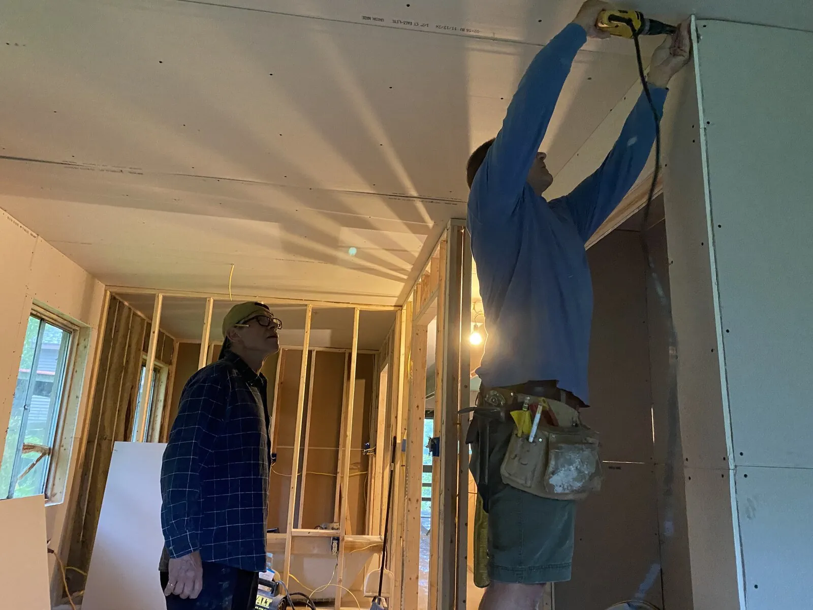 Two volunteers installing drywall on a ceiling frame